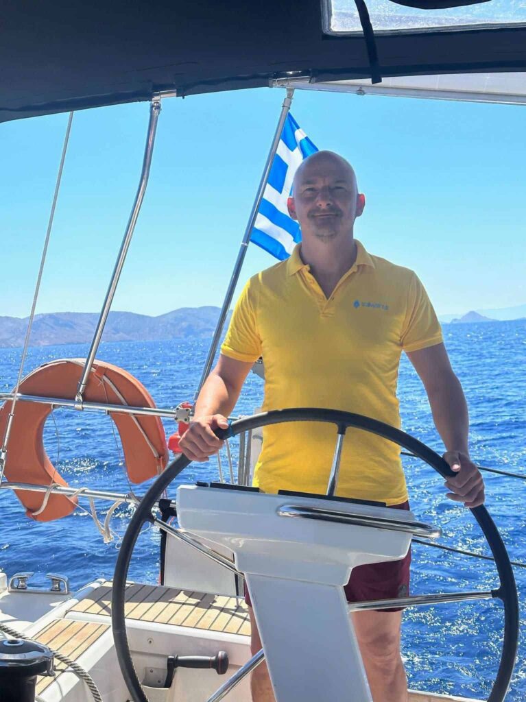 Skipper Tobias steuert ein Segelboot im Sailwithus-T-Shirt