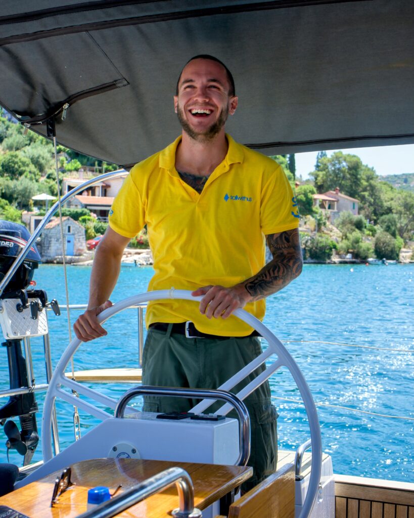 Skipper Tobi steuert ein Segelboot im Sailwithus-T-Shirt