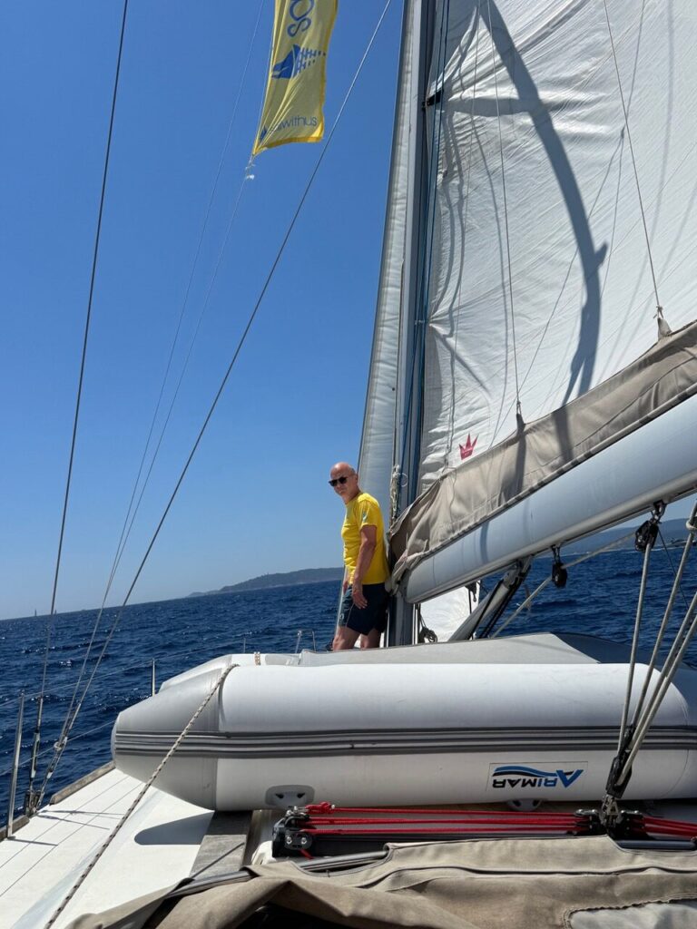 Skipper Matthias steuert ein Segelboot im Sailwithus-T-Shirt